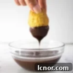 hand dipping a madeleine into a bowl of chocolate