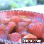A bowl of fresh summer strawberries with olive oil, basil, and honey glaze, ready to be served. A healthy and gourmet dessert option.