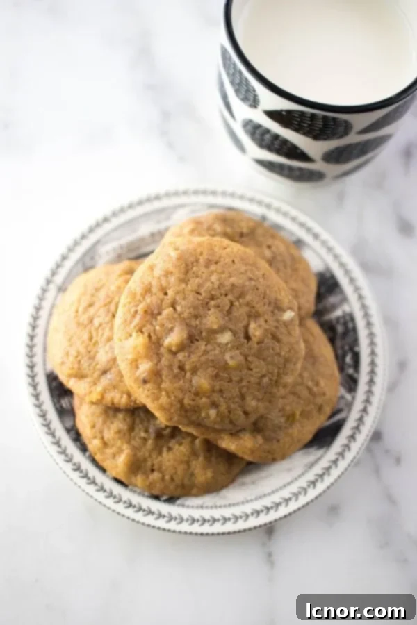 date cookies stacked on a black and white plate and a small cup of milk