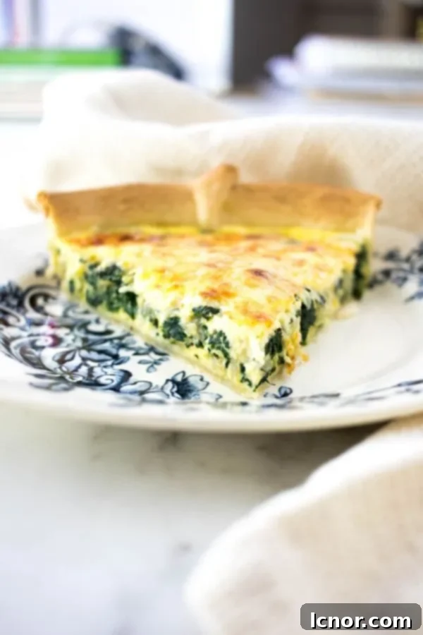 a slice of yellow cheese and spinach quiche Florentine on a blue and white floral plate