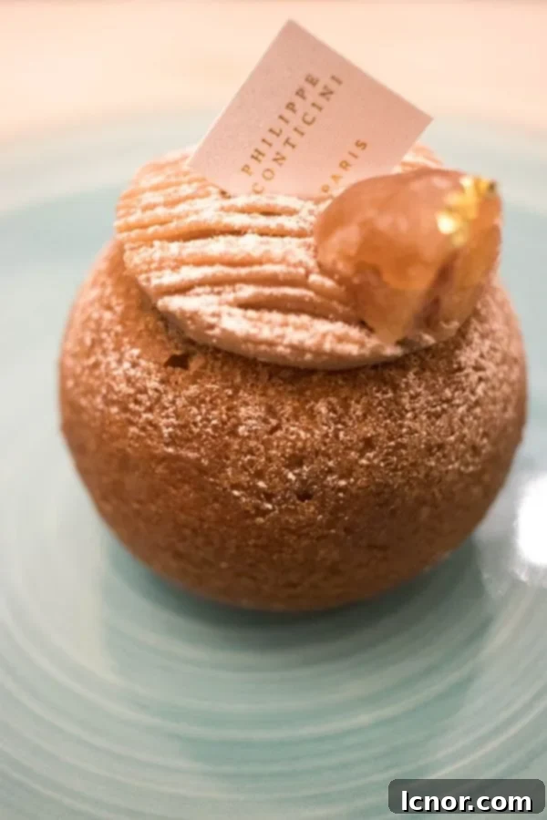 A delicate chestnut pastry puff topped with a chestnut, served on an aqua plate.