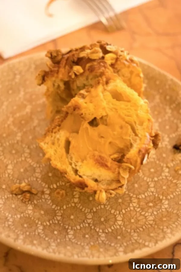 A close-up of a golden caramel croissant, with caramel gently oozing out, a must-try food in Paris.