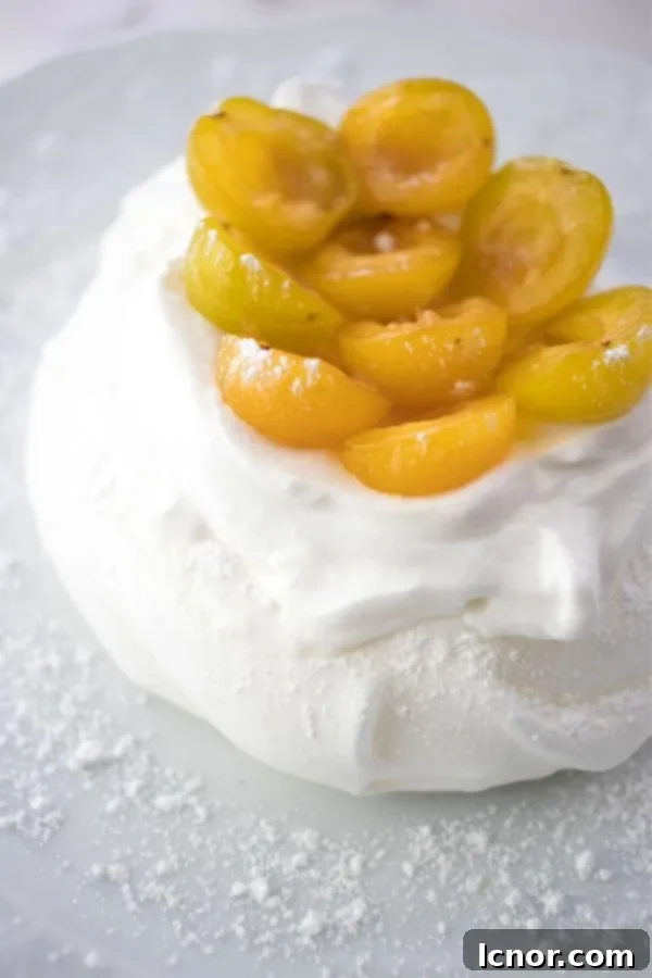 A pair of beautifully arranged mini Schaum Torte tartelettes on a crisp white plate, elegantly topped with fresh yellow mirabelle plums, ready to be enjoyed.