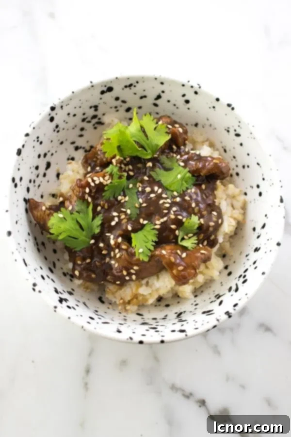 Strips of Asian chicken in a white and black speckled bowl with a spoon, waiting to be cooked.