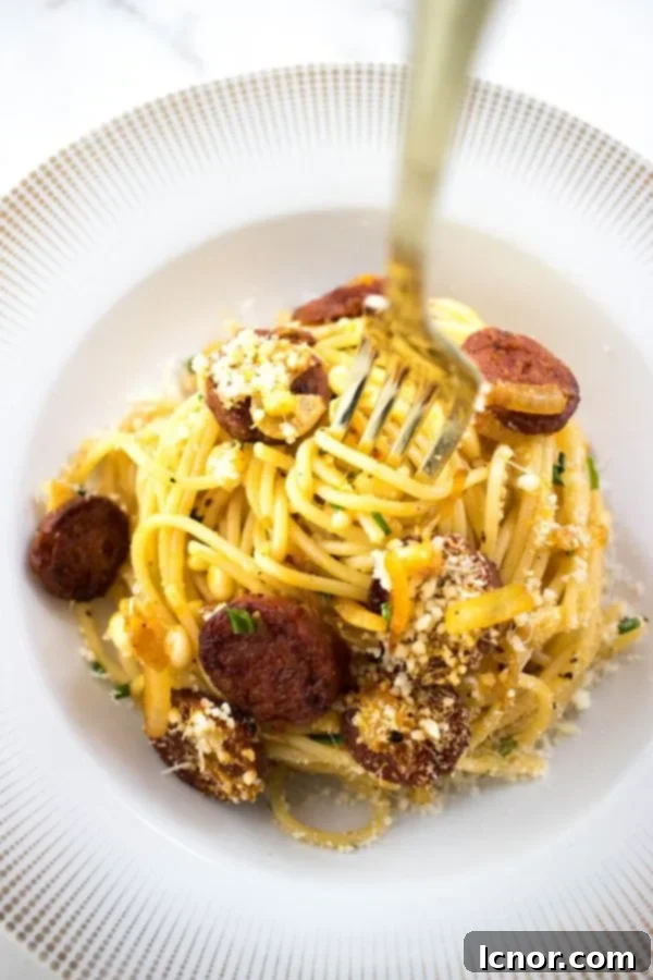A gold fork twirling in a bowl of creamy chorizo spaghetti, highlighting the rich colors and texture of the dish.