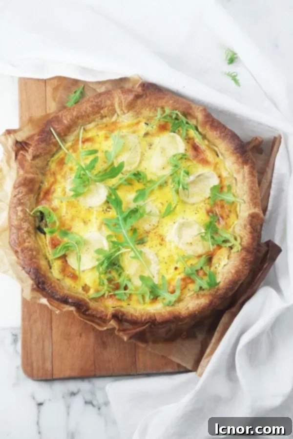 A freshly baked French goat cheese zucchini quiche on a rustic wooden cutting board.