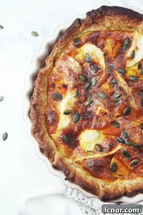 A vibrant pumpkin and goat cheese quiche, golden brown and ready to serve.