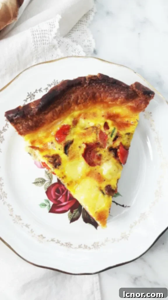 A delightful slice of Mediterranean quiche presented on a white and gold plate, adorned with a delicate rosebud.