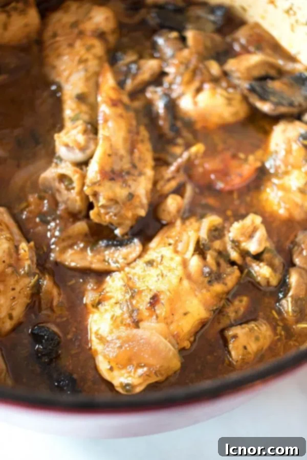 close up of Chicken Chasseur French slow cooked chicken stew in a red Le Creuset Dutch Oven