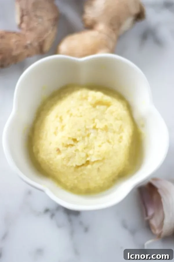 an overhead photo of garlic ginger paste surrounded by fresh garlic and fresh ginger