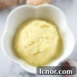 an overhead photo of garlic ginger paste surrounded by fresh garlic and fresh ginger