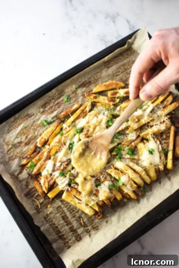 Pouring rich, homemade gravy generously over a freshly baked batch of crispy Disco Fries, before adding the cheese.