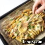 Pouring rich, homemade gravy generously over a freshly baked batch of crispy Disco Fries, before adding the cheese.