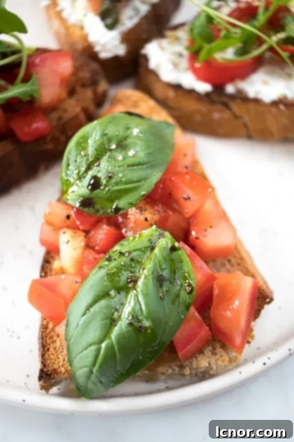 Close-up of a perfectly toasted bruschetta slice, topped with finely diced fresh tomatoes, fragrant green basil leaves, and a glossy sheen of olive oil, ready to be enjoyed.