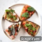 a beige speckled plate with bruschetta on it with tomatoes, basil, black olives, garlic and olive oil