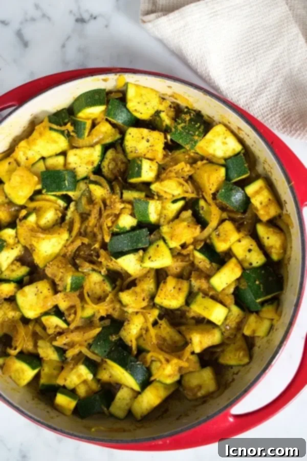 Indian zucchini curry in a red Le Creuset skillet, showcasing its vibrant color and texture.