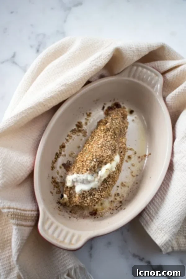 Philadelphia chicken in a cream dish wrapped with a cream dish towel, showcasing the golden-brown crust and creamy filling