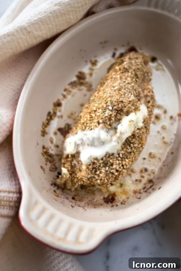 Philadelphia chicken in a cream baking dish wrapped in a cream dish towel, ready for the oven