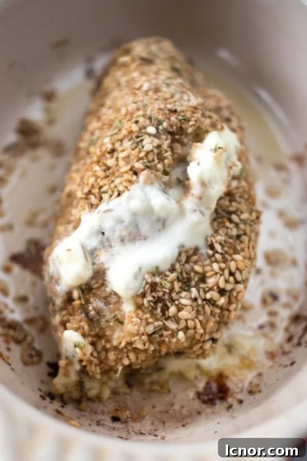 A close up of chicken stuffed with Philadelphia and coated in sesame seeds, freshly baked