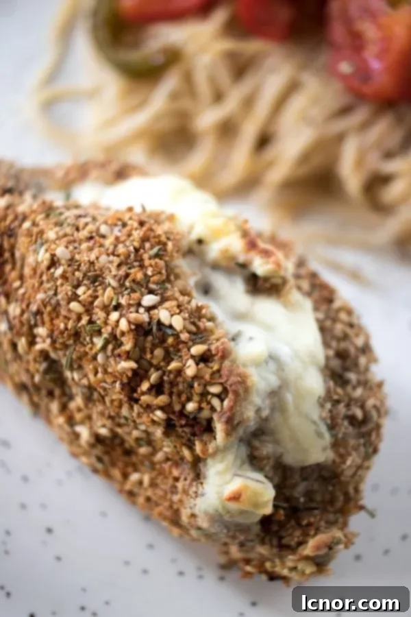 Philadelphia stuffed chicken topped with sesame seeds with spaghetti in the background, a complete meal