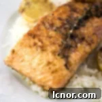 salmon meunière on a white plate with white rice and lemon slices on the side