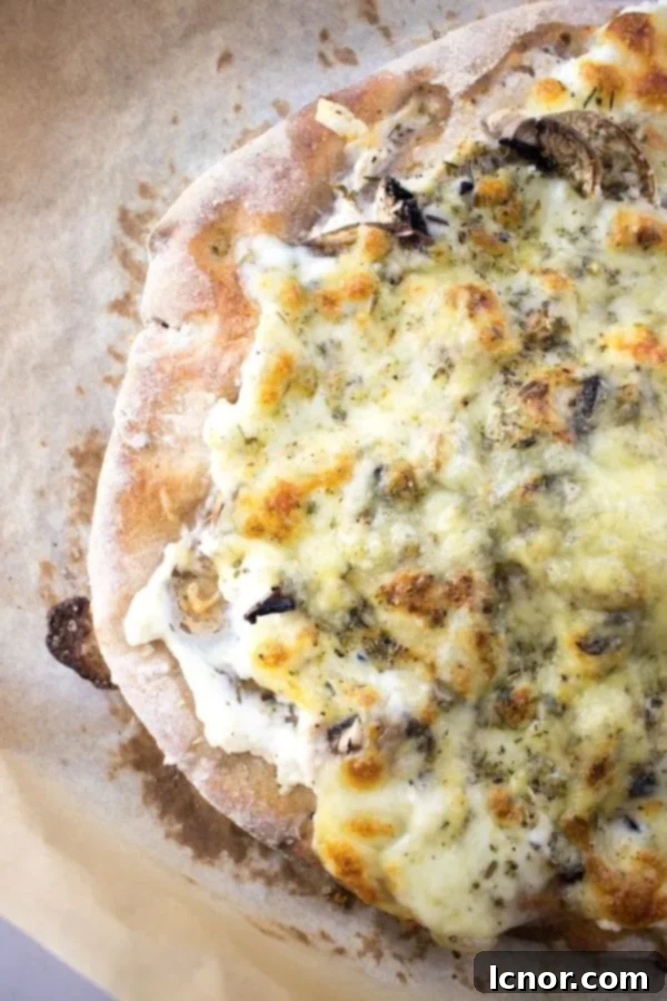 sourdough pizza on parchment paper with cheese and mushrooms
