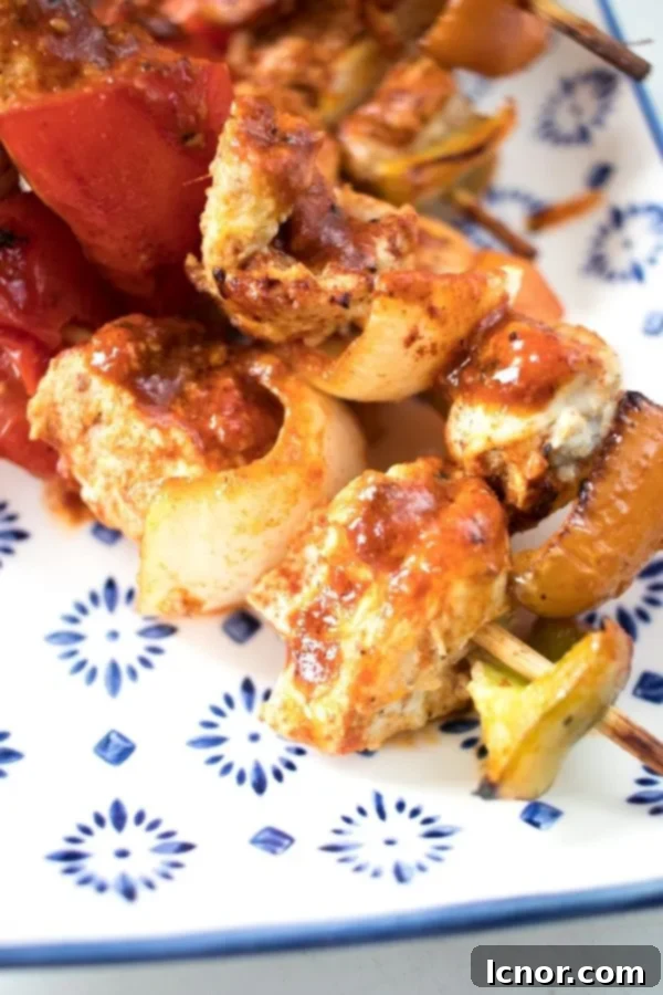 Close-up of a flavorful chicken skewer with vibrant pieces of red pepper and onion, ready for oven baking