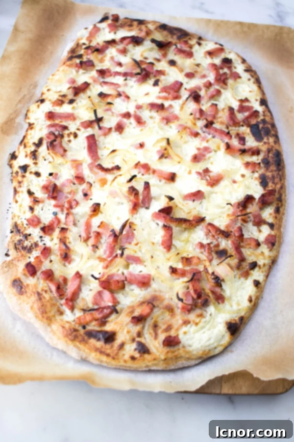 A delicious Flammekueche (Alsatian Pizza) with a thin crispy crust, creamy topping, and onions.