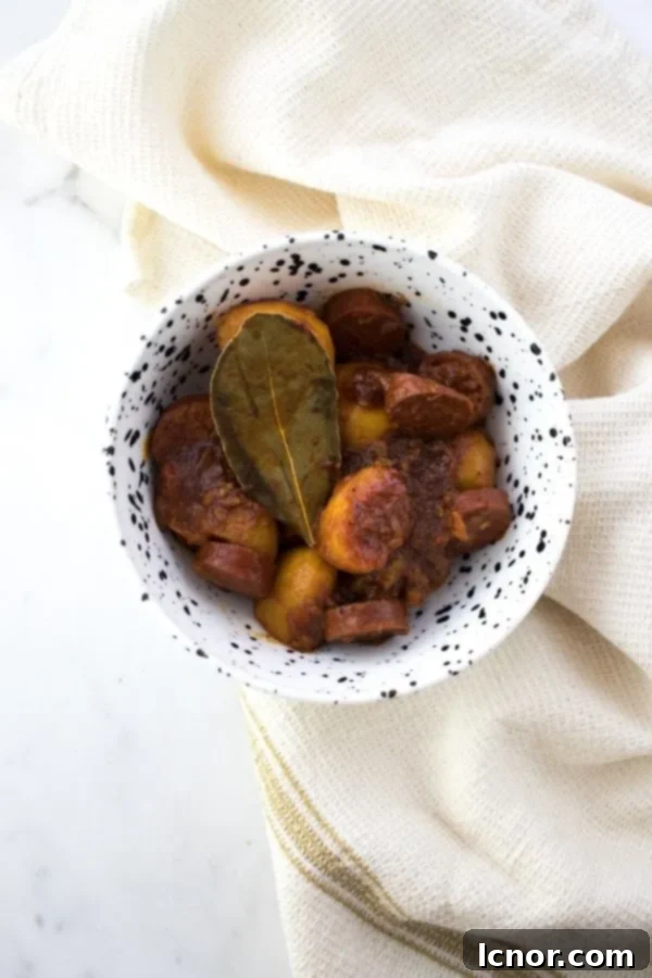 A bowl of tapas rioja potatoes and chorizo, garnished with a bay leaf
