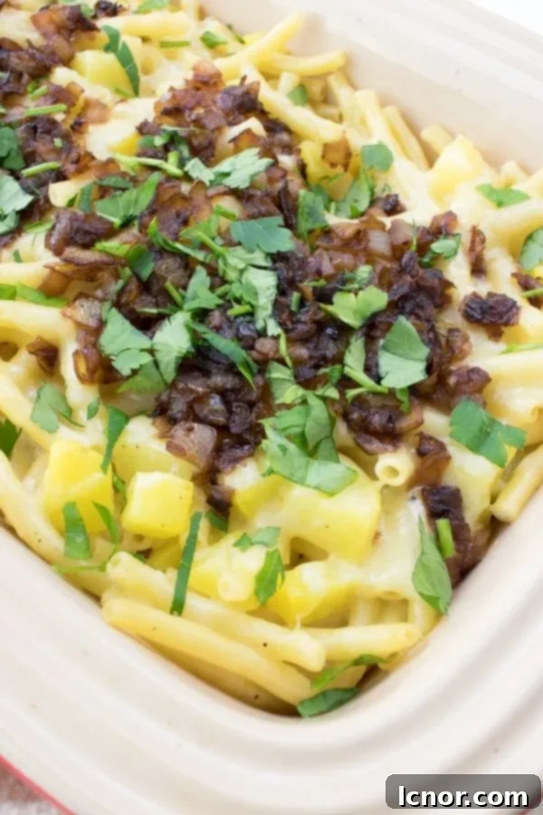 A close-up view of creamy Swiss alpine macaroni, topped with golden caramelized onions and a sprinkle of fresh green parsley, ready to be served.