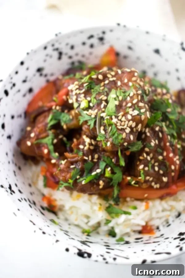 A bowl of Sweet and Sour Pork Kou Lou Yuk served with white rice, showcasing the vibrant colors and appealing texture of the dish.