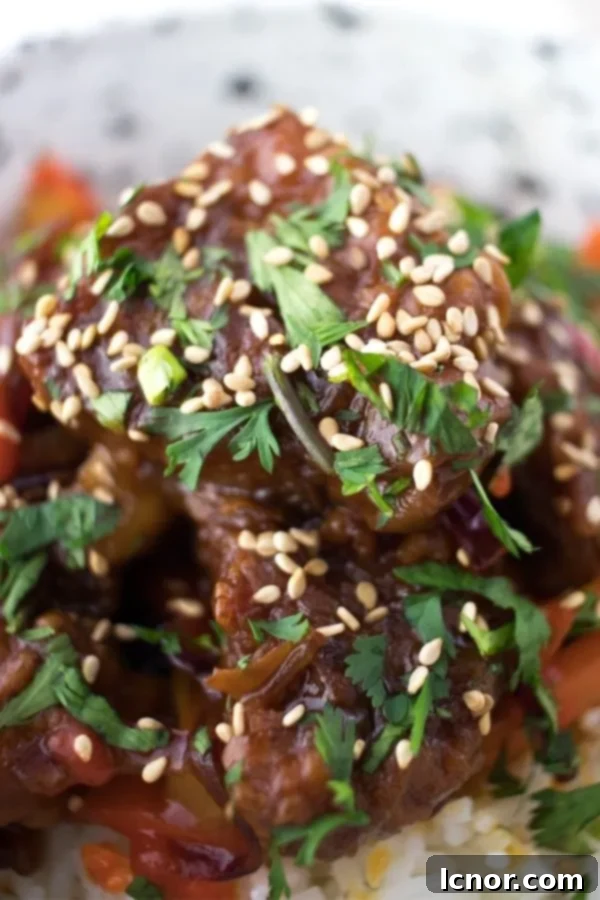 Close-up of crispy sweet and sour pork on a bed of rice, garnished with fresh cilantro.