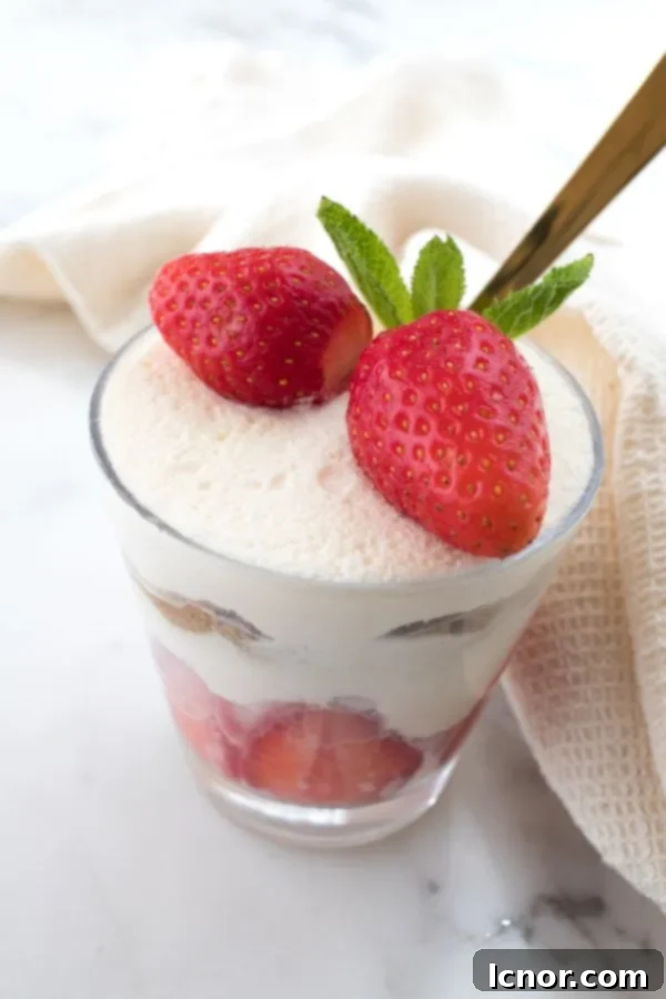 tiramisu alle fragole in a cup with a spoon, garnished with a fresh strawberry