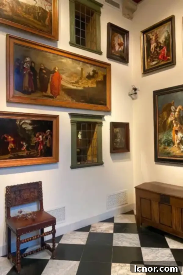 The grand entryway of the Rembrandt House in Amsterdam, showcasing period oil paintings and a striking black and white tiled floor
