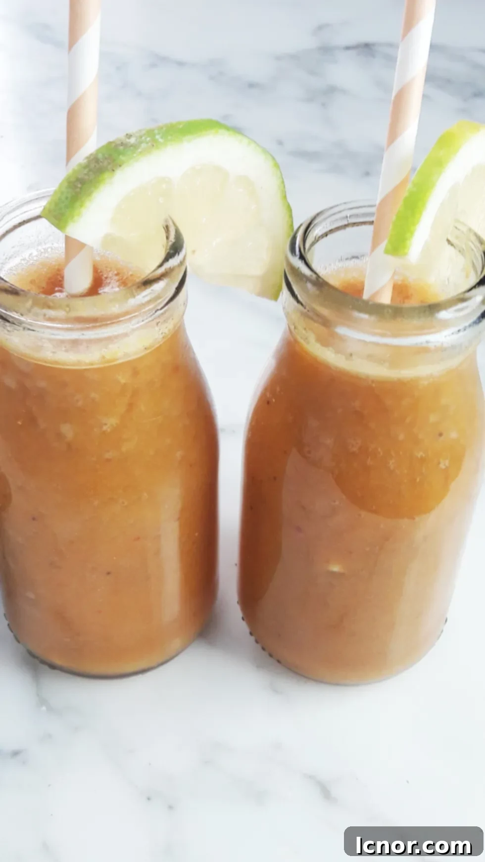 Bright orange Mango Banana Carrot Smoothie in a glass jar, garnished with a slice of orange and a colorful straw, perfect for a healthy breakfast. A Hedgehog in the Kitchen.