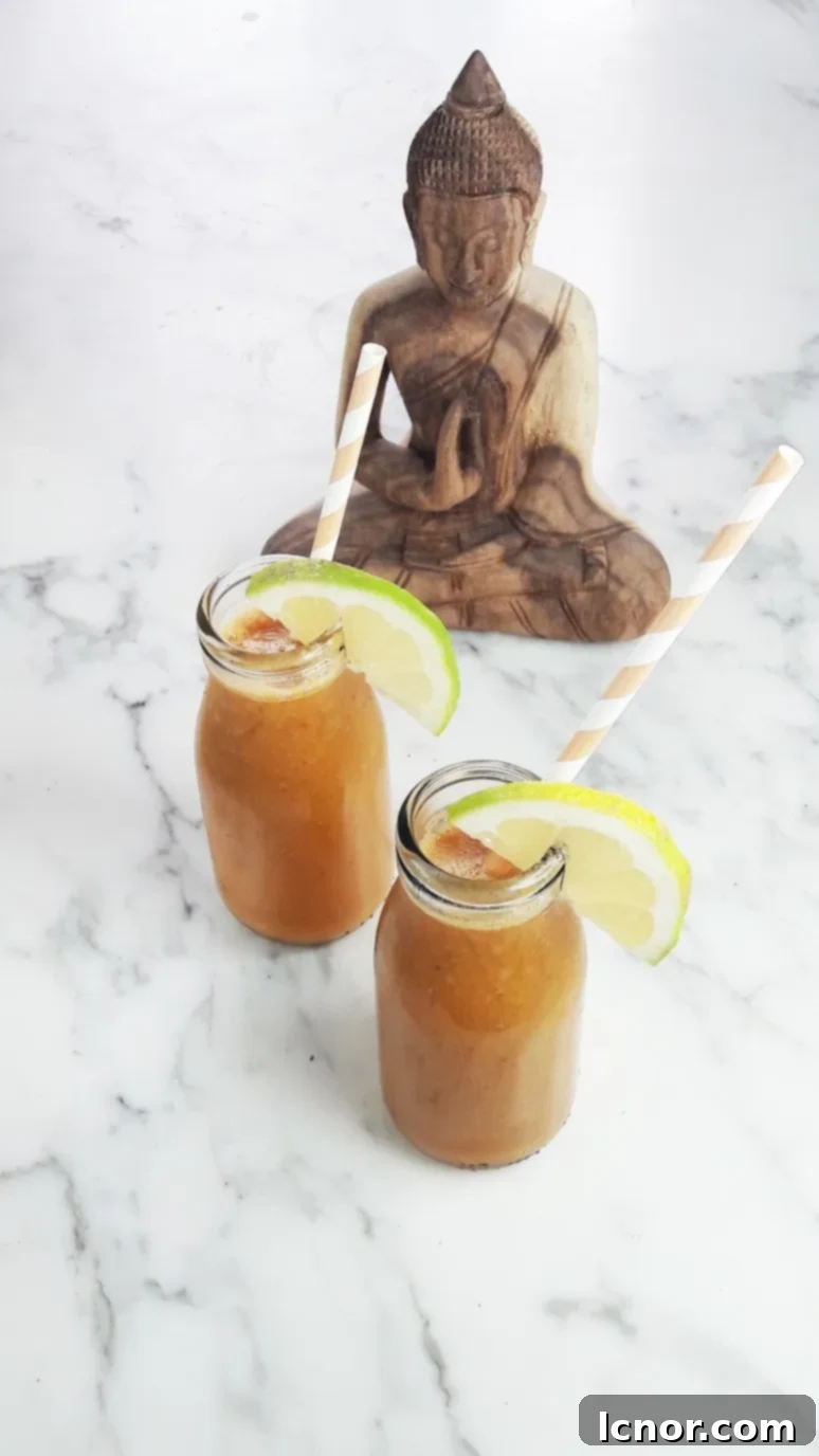 Close-up of a Mango Banana Carrot Smoothie, showing its smooth texture and rich color, with a yellow straw. A Hedgehog in the Kitchen.