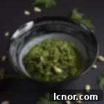 Vibrant green coriander pesto in a small bowl, garnished with fresh coriander leaves.