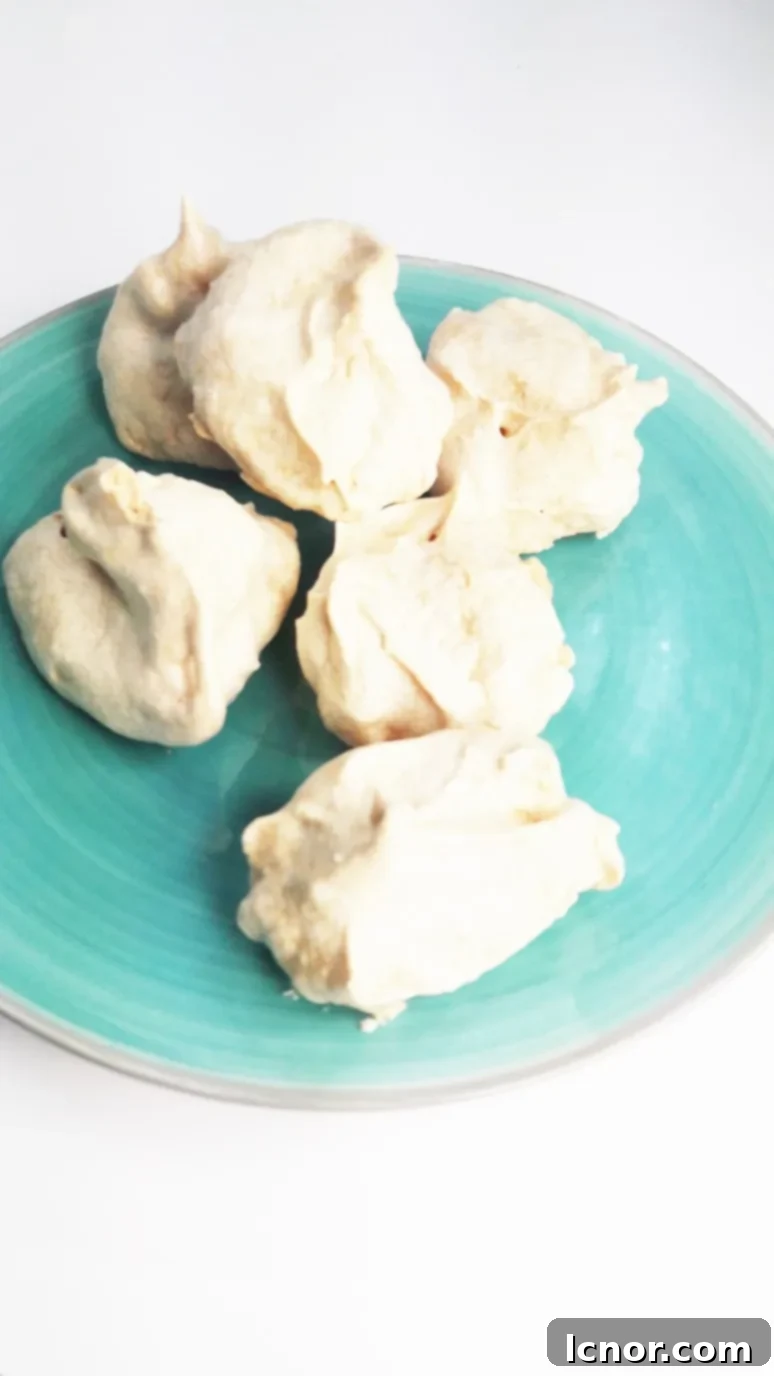 Two kaffir lime meringues on a blue plate, with kaffir limes in the background