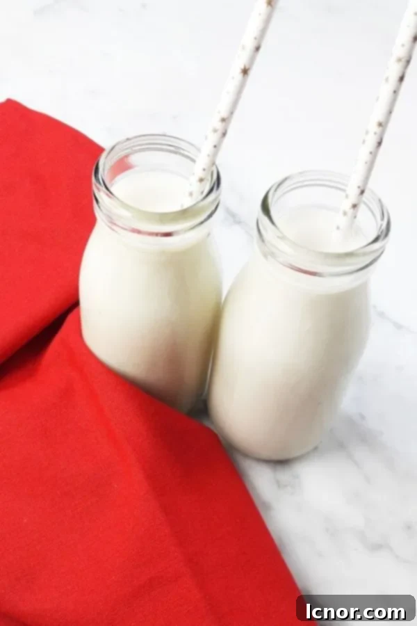 Creamy banana lassi in a glass bottle on a red tea towel, served on a marble table