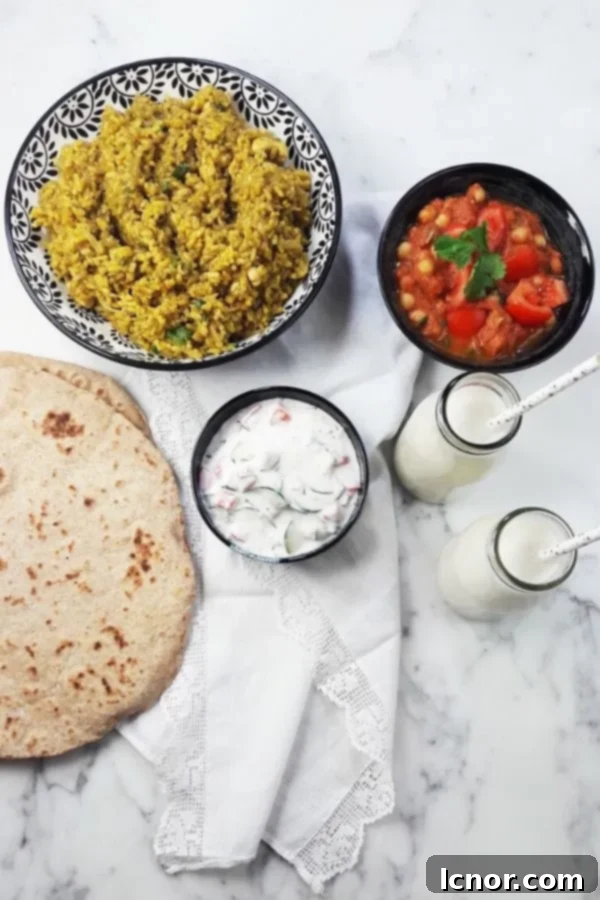 Banana lassi served with traditional Indian dishes like raita, cashew rice, and Indian cheese naan bread