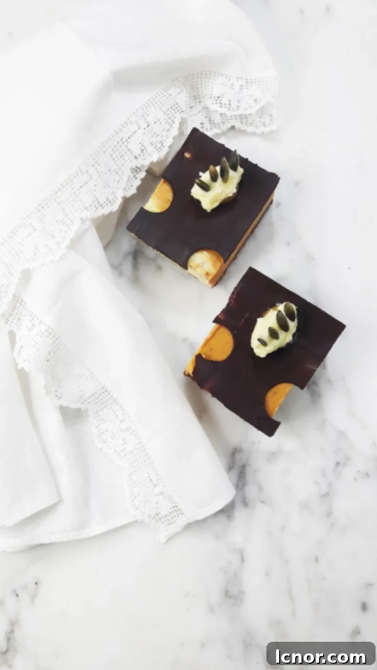 Close up view of a pumpkin cheesecake bar revealing the crunchy speculoos crust and smooth pumpkin cheesecake layer, with a subtle hint of chocolate topping.