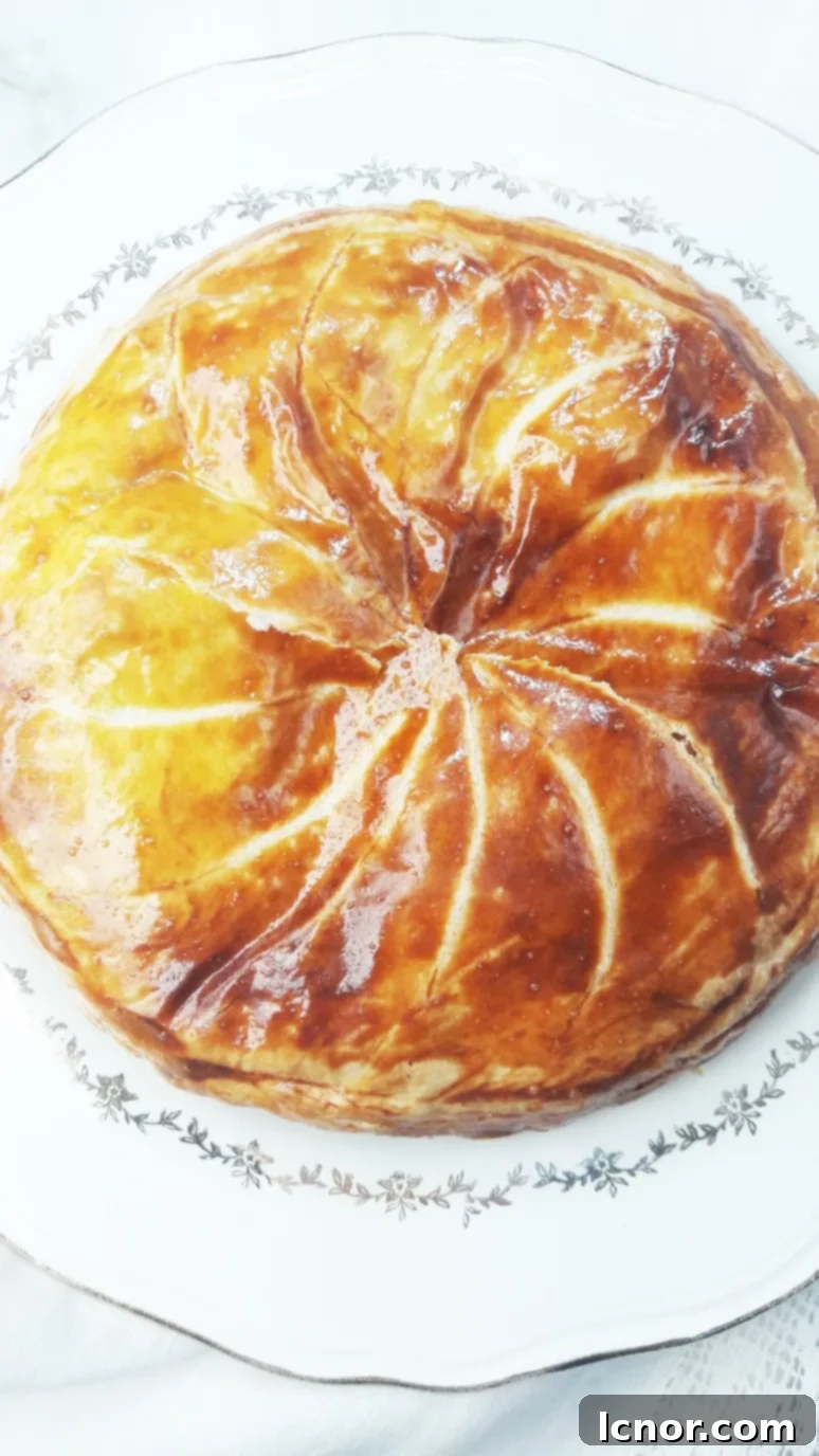 A slice of caramelized apple galette des rois revealing the hidden fève (ceramic figurine). | ahedgehoginthekitchen.com