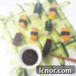 A close-up of a vegan sushi roll, featuring rice, sweet potato, and beet, on a woven cucumber mat.