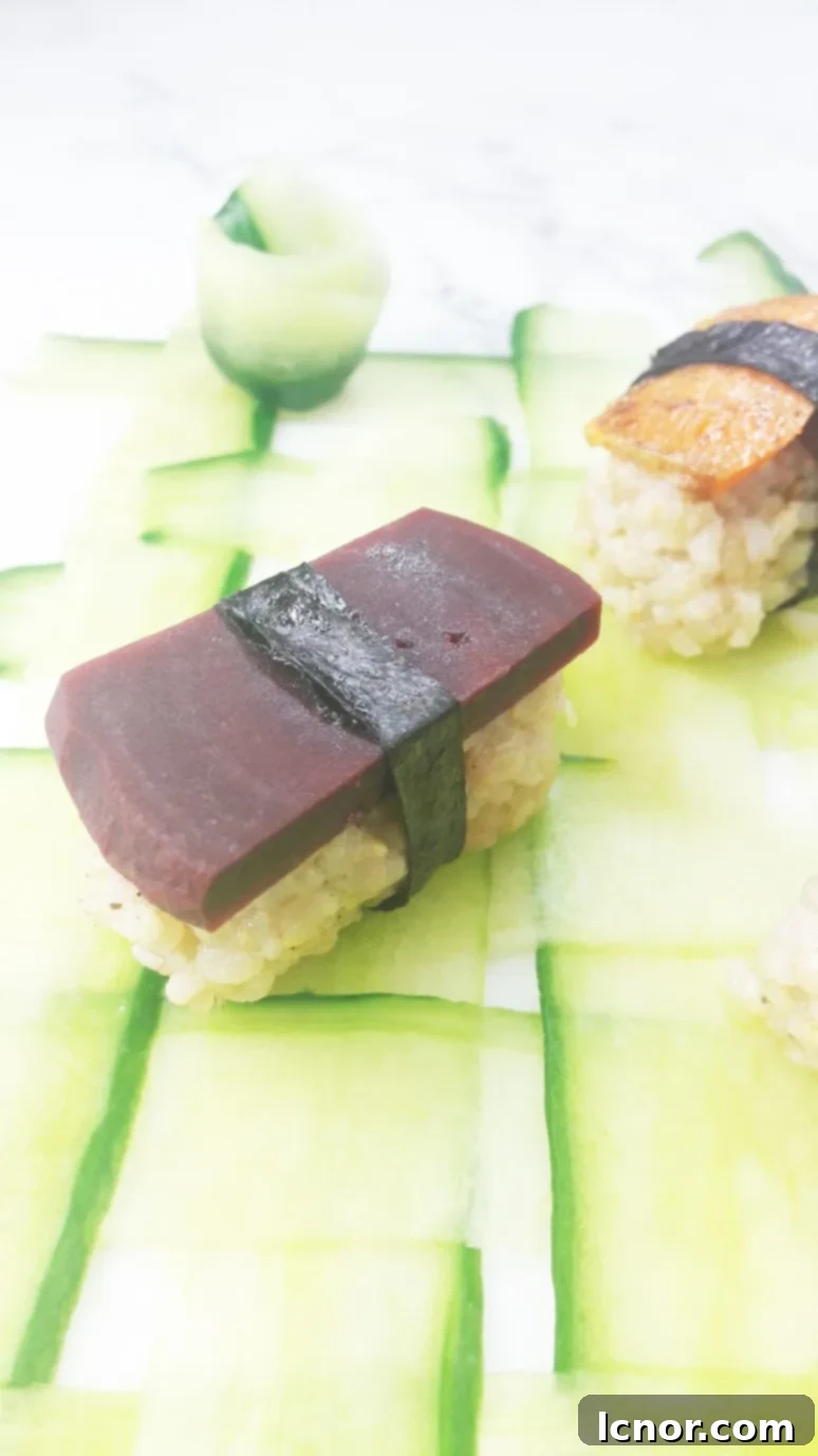 Close-up of vegan sushi featuring orange sweet potato and red beet slices, wrapped in nori and arranged artfully.