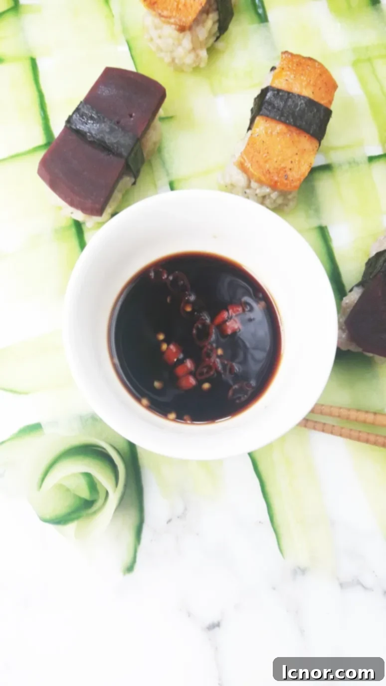 Vegan sushi pieces on a woven cucumber mat, with a small dish of spicy soy dipping sauce.