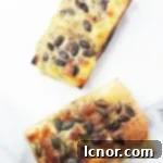 Crispy cheese toast on a sliced French baguette, adorned with golden melted cheese and vibrant green pumpkin seeds.