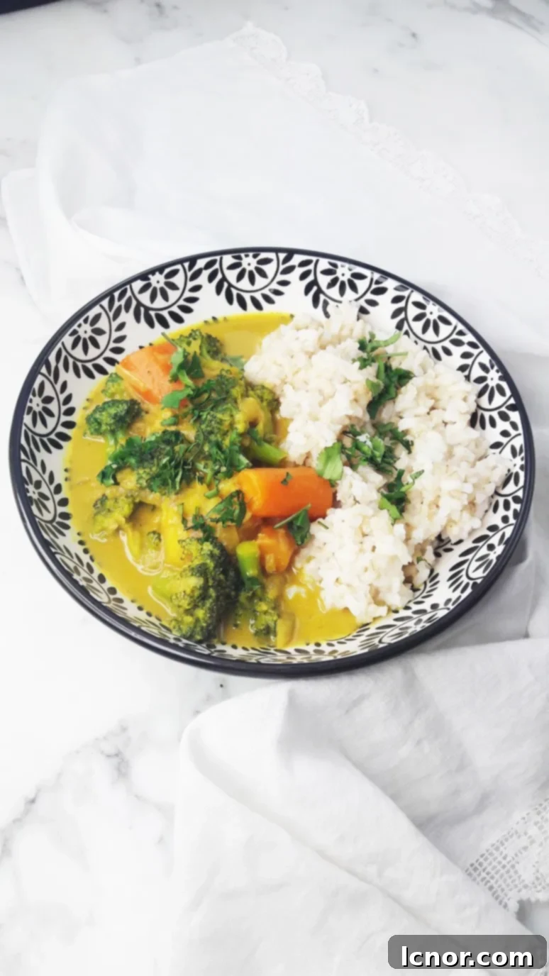 A bowl of fresh vegan broccoli carrot potato coconut curry, garnished with cilantro.