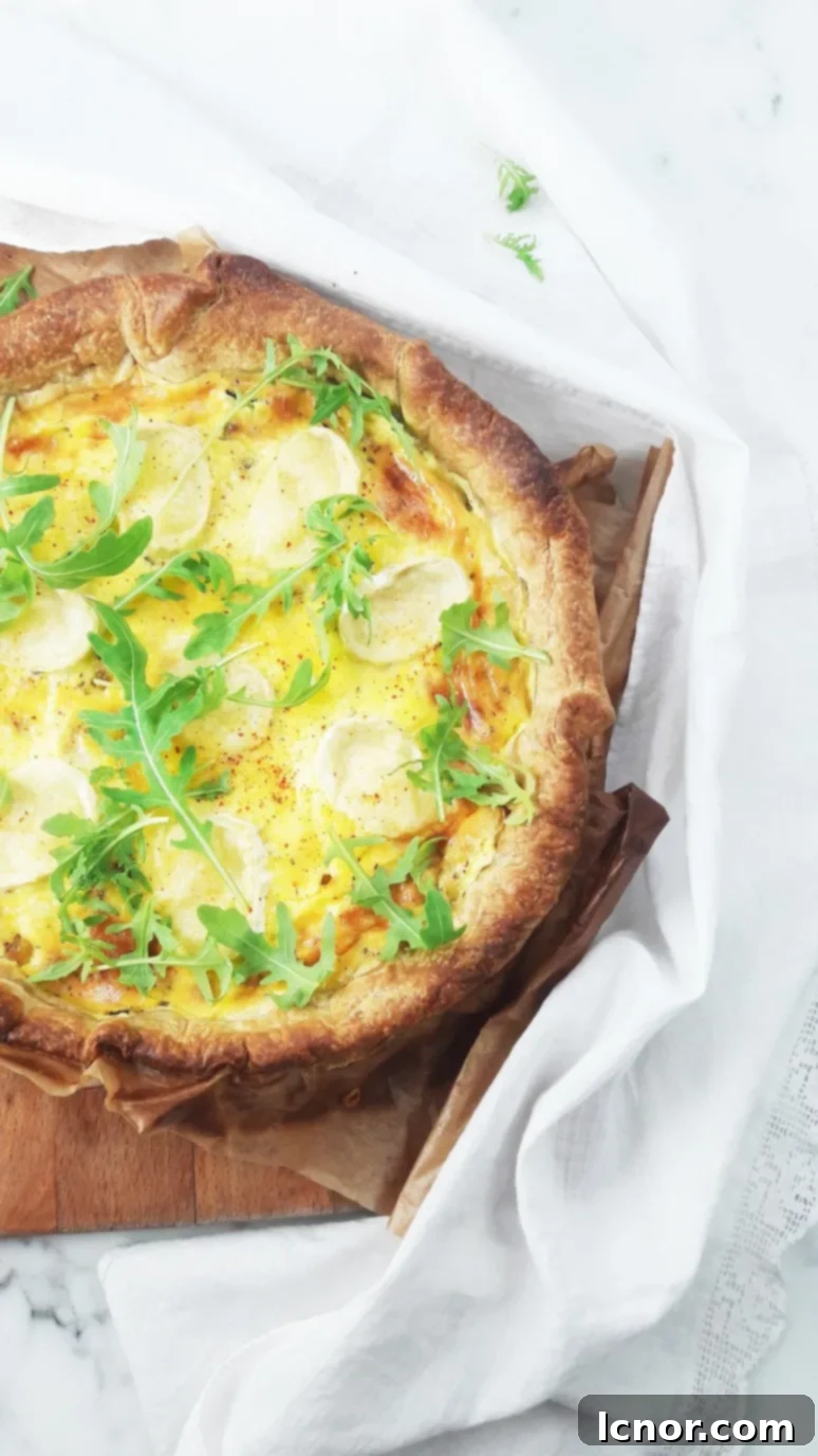 A beautifully baked Goat Cheese Zucchini Quiche, golden brown and ready to be served, garnished with fresh rocket lettuce.