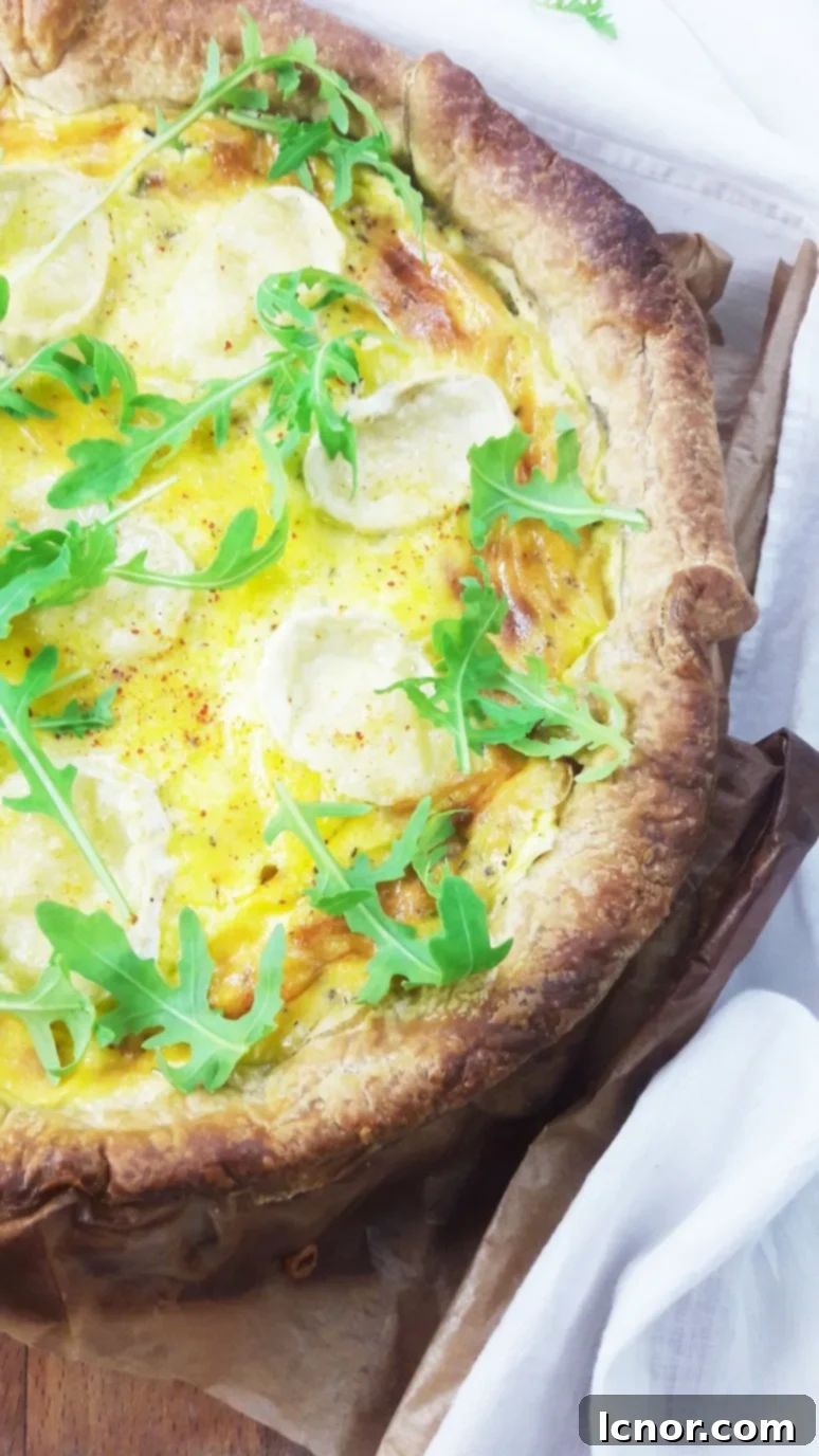 A close-up on the perfectly golden crust of the Goat Cheese Zucchini Quiche, with the creamy filling visible.