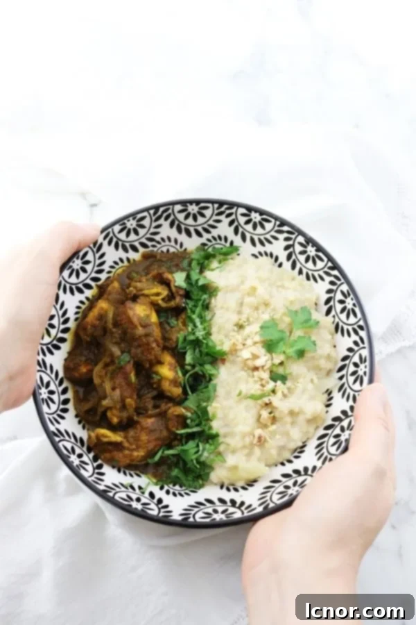 Burmese chicken curry with coconut rice in a black and white bowl